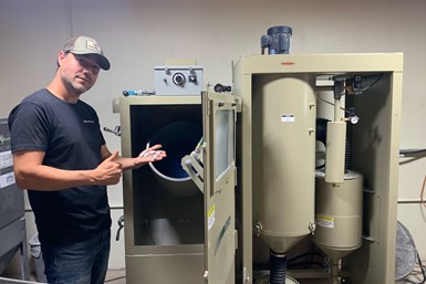 A photo of Felipe Salazar gesturing toward his new blasting cabinet from Clemco