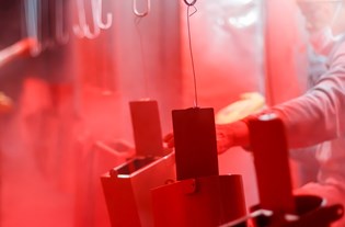 worker spraying on a red powder coating onto parts