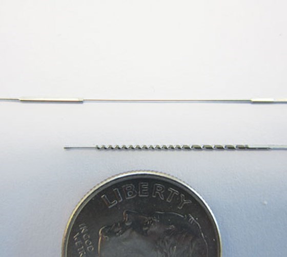 complex guidewires laid next to a dime to show how small they are