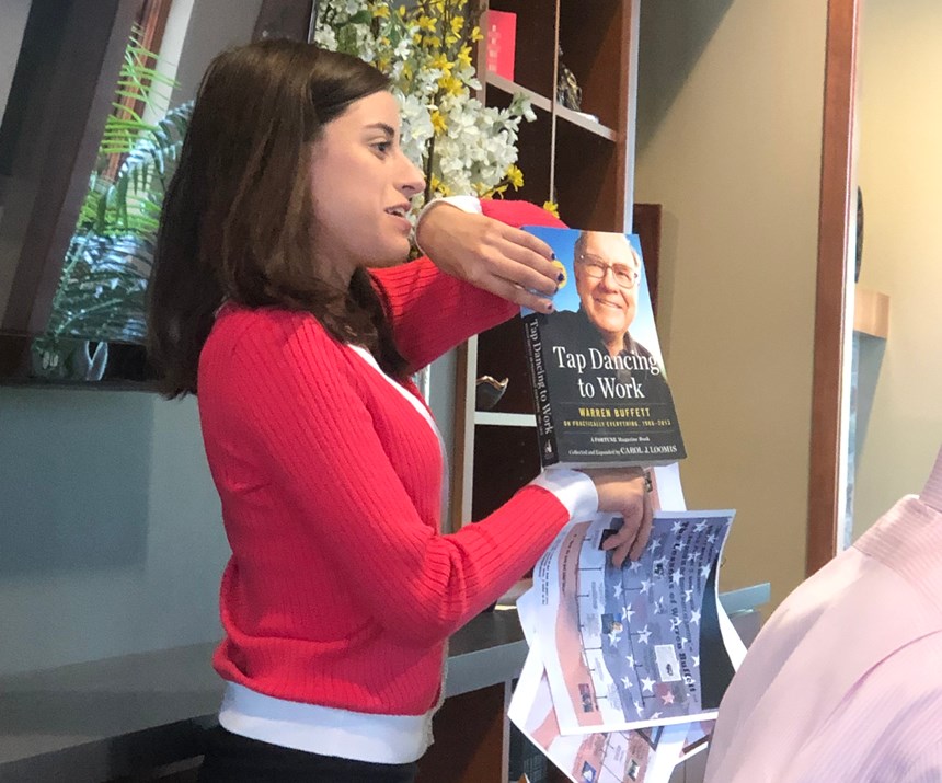 female intern holding up book authored by Warren Buffet