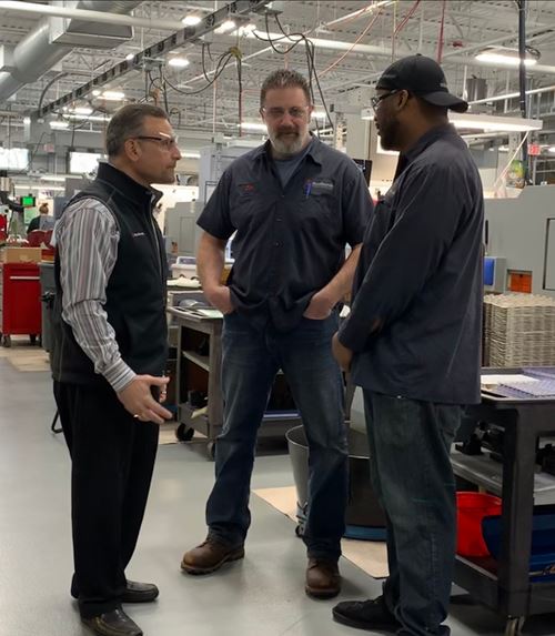 Michael Tamasi (left), stands with other AccuRounds employees on shop floor