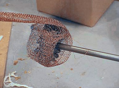 El primer paso en la limpieza del barril es envolver gasa de cobre alrededor del diámetro exterior de un cepillo de alambre redondo, en el extremo de una varilla de extensión.