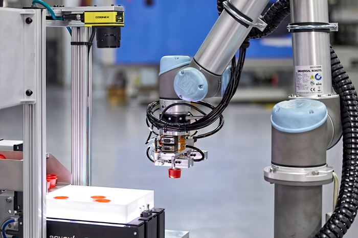 UR cobot uses a vision system to pick up and orient caps before assembling them onto a molded part.