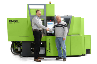 two men shaking hands in front of an Engel victory 55 machine