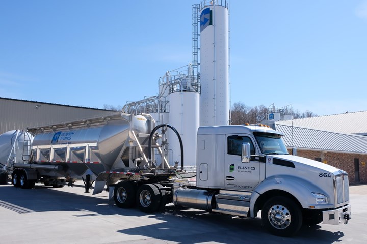 Tanker truck with silo equipment in the background. 