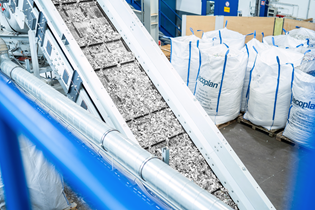 ground plastic on a conveyor, with regrind bags in the background