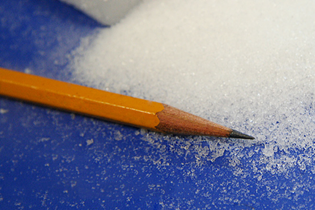 photo of a pencil next to a pile of dry ice microparticles to show their scale
