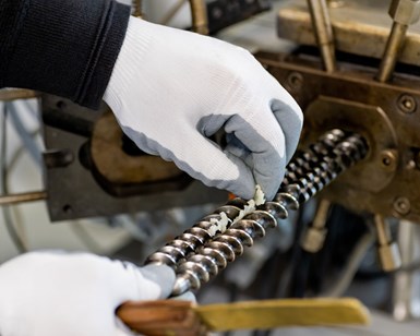 Photo of two hands removing material from compounder pulling screw