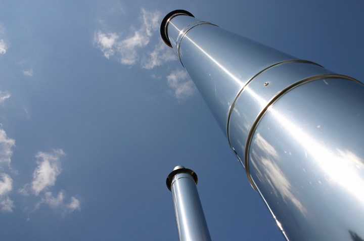 Photo of 2 industrial chimneys with blue sky and light clouds in background
