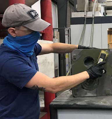employee clearing sand from a 3D printed tool 
