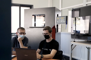 A photo of two people from 9T Labs working at a computer