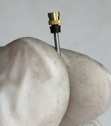 A photo of a person holding the micro part for AntiShock's medical device between their thumb and pointer finger.