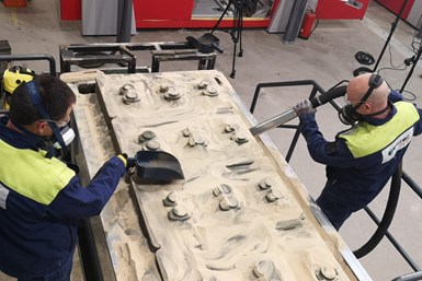 A photo of two Hetitec employee removing parts from a bed of sand