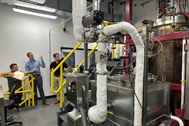 Travis (far left) and Max Egan (far right) stand next to a plasma column that synthesizes EV battery materials at the 6K Battery Center of Excellence.