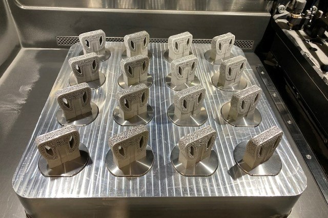 16 3D printed spine implants printed on individual pucks within a build plate