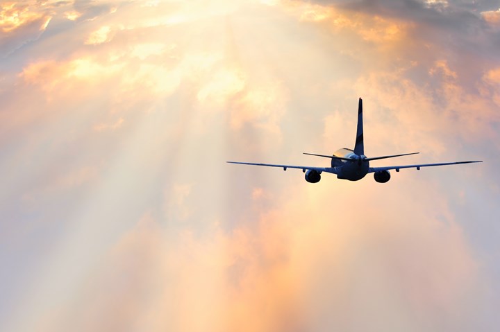 Passenger plane flying at sunset.