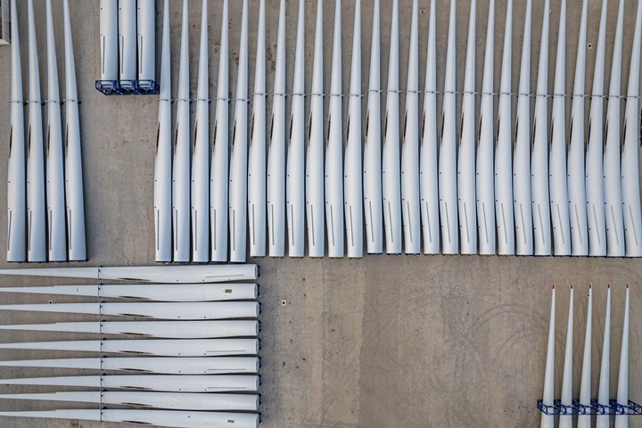 Aerial view of the blade parts of a wind turbine parked on a cement yard.