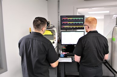 A photo of two J&W Swiss operators looking at a screen displaying data from Datanomix Fusion
