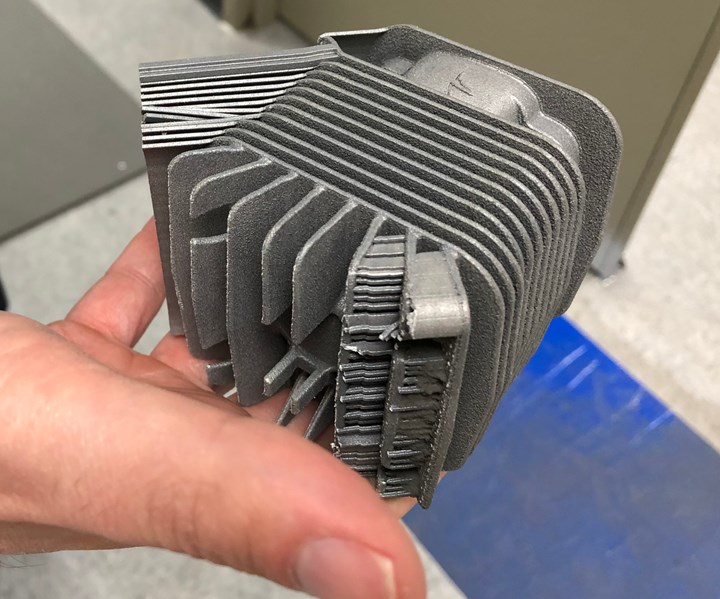 early version of an additive-manufactured engine cylinder with support structures still visible 