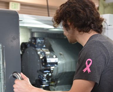 A photo of a TECMA intern opening the door of a machining center