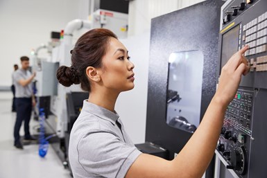 A stock photo of a woman operating a CNC machine