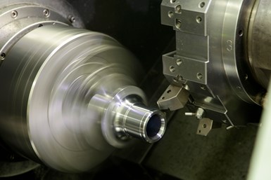 A second photo of a lathe extending a cutting tool to a workpiece undergoing turning