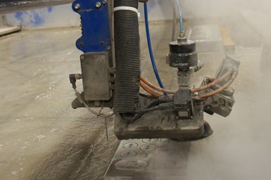 A photo of a Wardjet waterjet cutting machine in use. Hypertherm branding stands out on the intensifier pump.