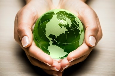 A stock photo of a person cupping a green globe in both hands