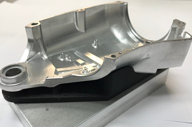 A 3D-printed fixture holds a CNC-machined metal part for inspection in a CMM. 