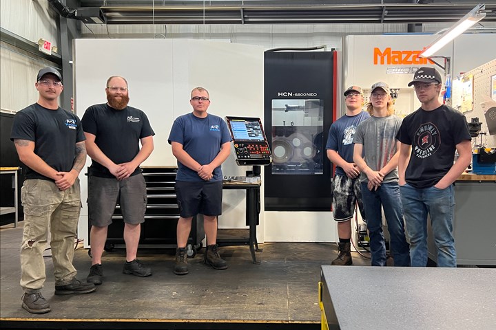 A photo of six young men standing in front of a Mazak machining center.