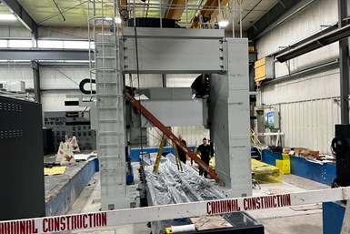 A photo of a large machine under installation. The shop floor's foundation has been lowered to accommodate the machine's size.