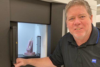 A photo of Kevin Legacy standing in front of a Zeiss x-ray scanning machine.