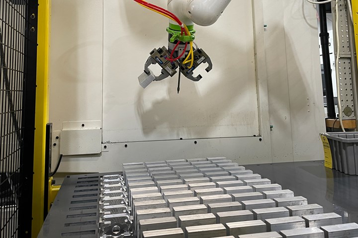 A photo of one of Wagner Machine's robot cells, with two grippers on the robot and a tray of parts below.