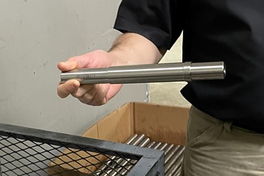 A photo of Tim Tremain holding a thin, cylindrical Freon pump shaft