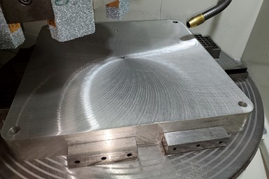 A photo of a flat build plate, with a grinder above and to the left side.