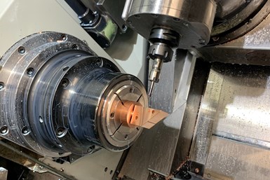 A photo of a live-tool CNC lathe with a spindle closing in on a square workpiece