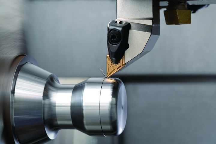 A close-up of a carbide insert removing metal from a cylindrical compnent mounted in a lathe. 