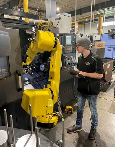 A Pro Products Inc. employee controlling a robot near a machine.