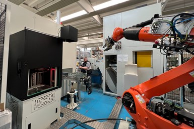 A robot in the middle of an automation cell, with visible access to several machine tools and postprocessing machines