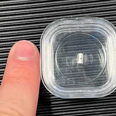 The photographer's finger next to a laser micromachined part. The par is about half as long as his fingernail, with features that are even smaller still.