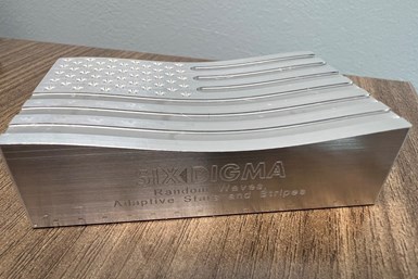 A machined block with an American Flag design on top and Six Digma's name engraved on the side. The top of the block has a contour .