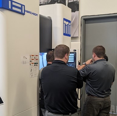 A group of manufacturers examines the M1 five-axis machine at the Hwach