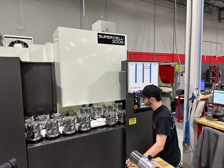 Photo of machine operator in front of Kitamura horizontal machining center with a large quantity of parts that have been machined.