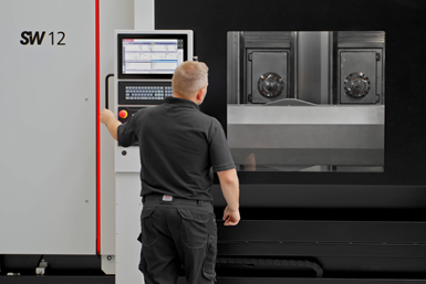 Person standing at the control of a machining center.