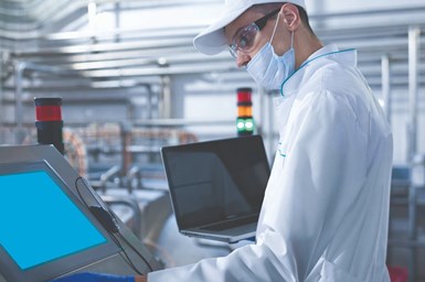 machinist wears mask and gloves while operating machine control