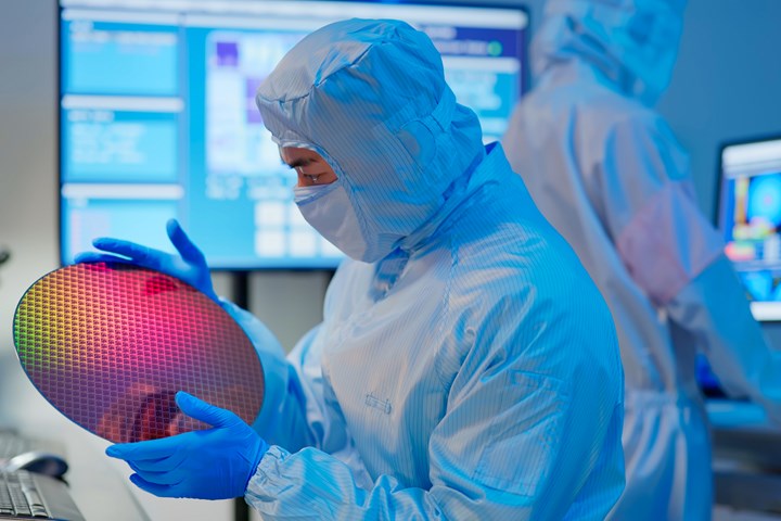 Image of employee at semiconductor fab looking at chip.