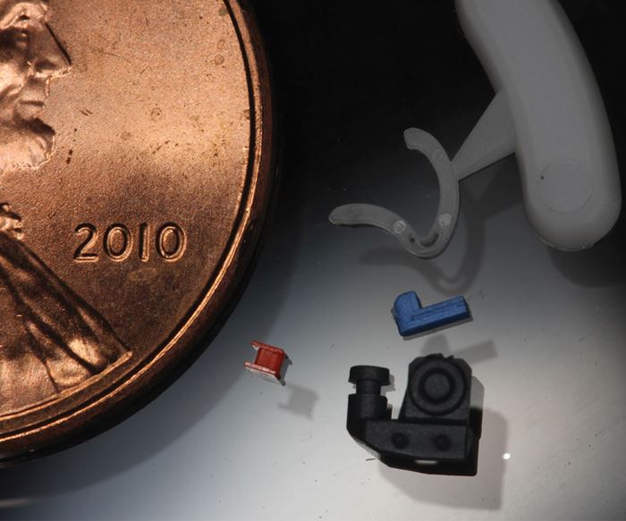 Tiny complex parts shown next to a penny to demonstrate relative size.